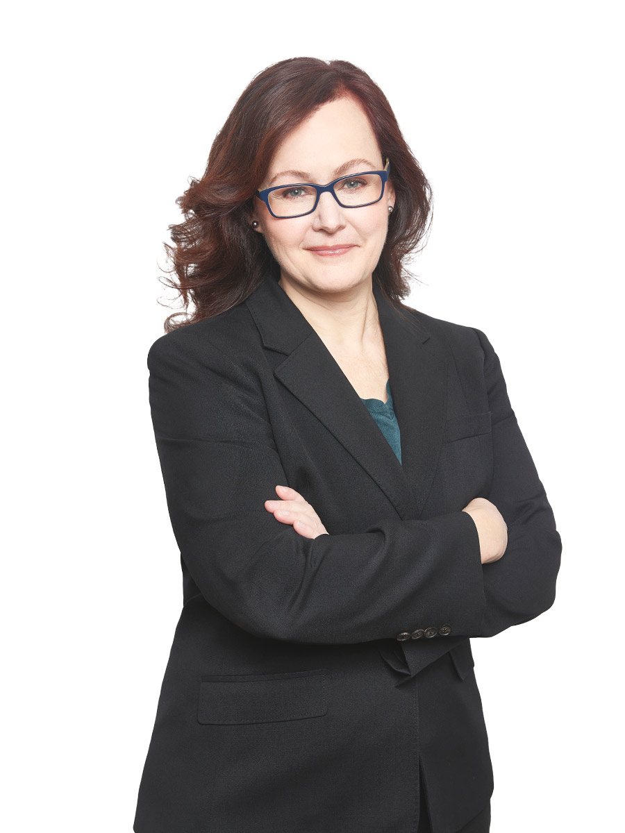 Portrait of lawyer Adrienne Lee in a black suit with arms crossed, wearing glasses, and presenting a professional and approachable demeanor on a white background.